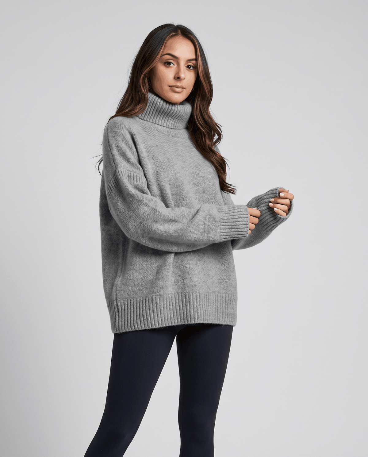 Gray Merino Wool Turtleneck Sweater worn by a female model from the side, featuring an oversized fit, high turtleneck collar, and ribbed cuffs.