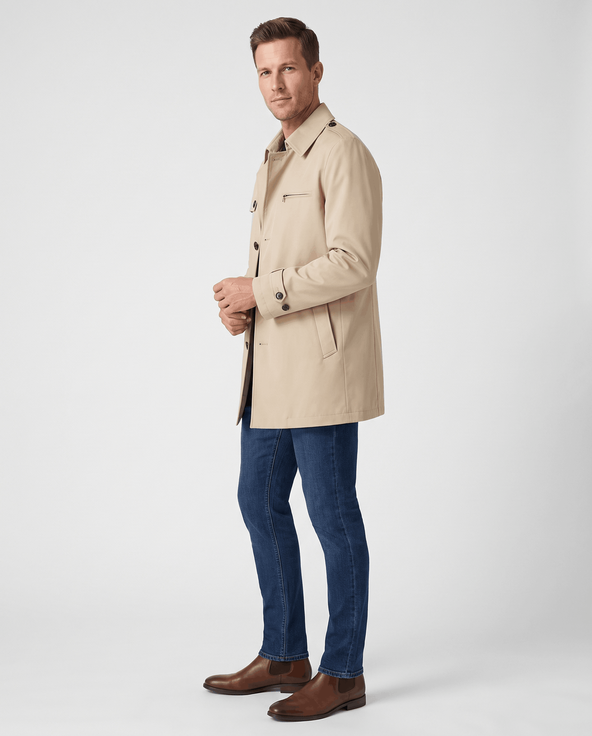 A man wearing a beige mid-length single-breasted trench coat with a button front and tailored fit, side view