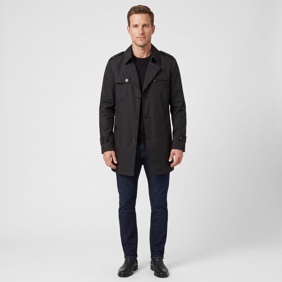 A man wearing a black mid-length single-breasted trench coat with a button front and tailored fit