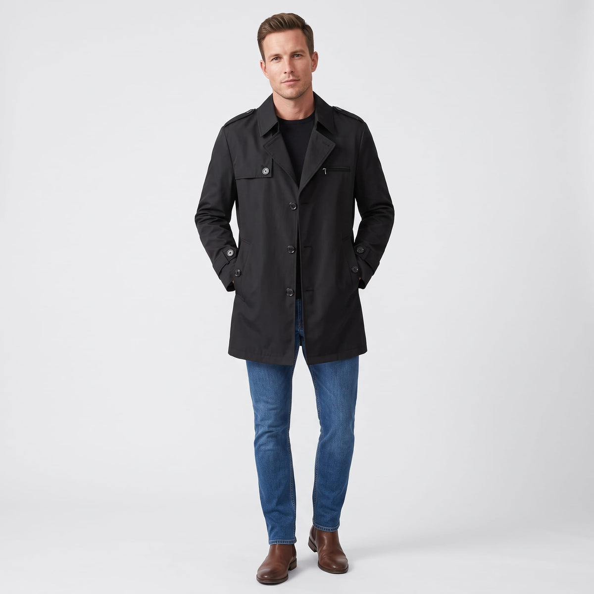 A man wearing a black mid-length single-breasted trench coat with a button front and tailored fit