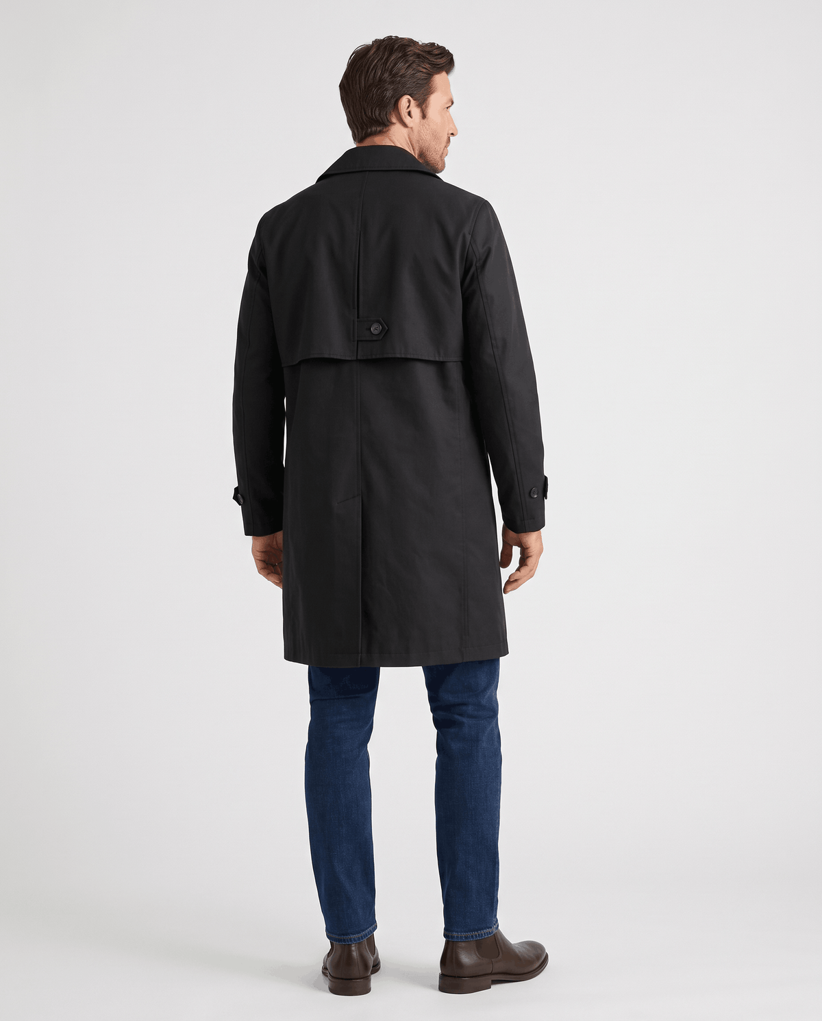 A man wearing a black mid-length single-breasted trench coat with clean lines, shown from the back