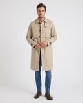 A man wearing a beige mid-length single-breasted trench coat with clean lines, a button front, and an easy layering fit