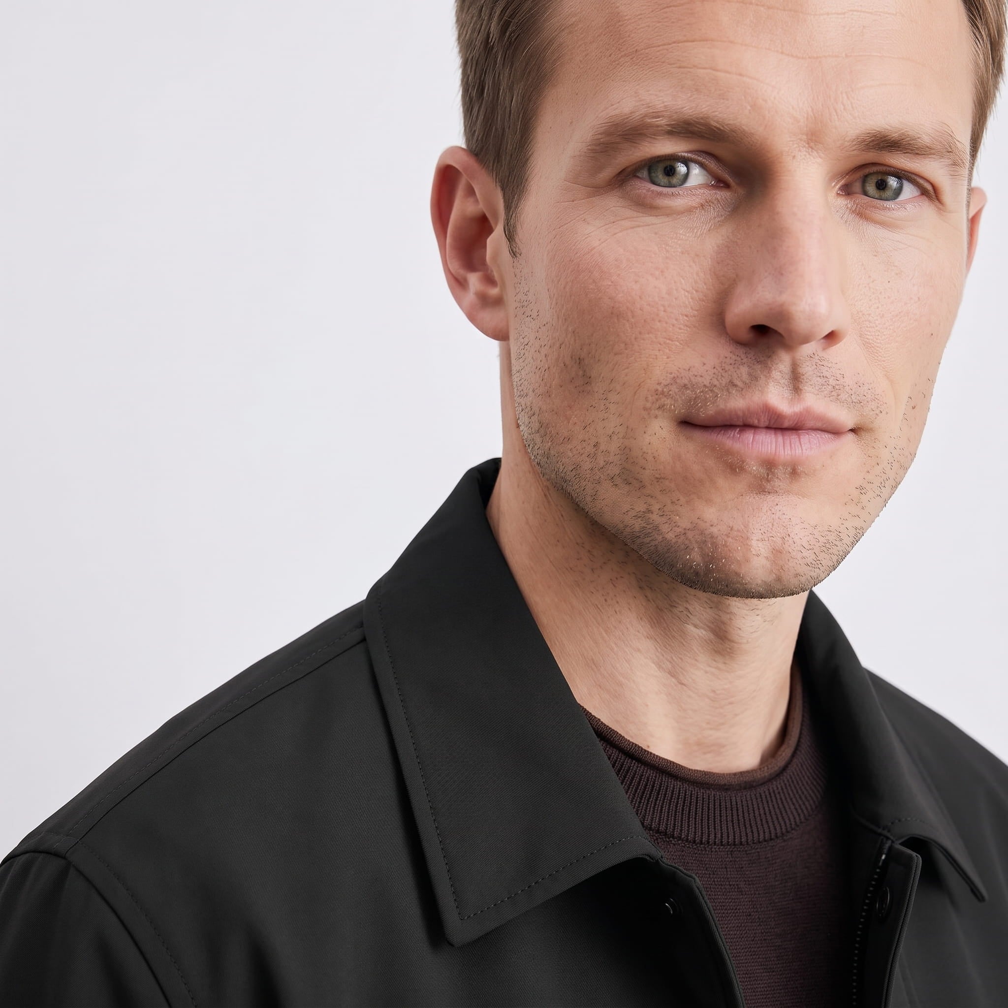 Close-up portrait of the male model wearing the black collared jacket.