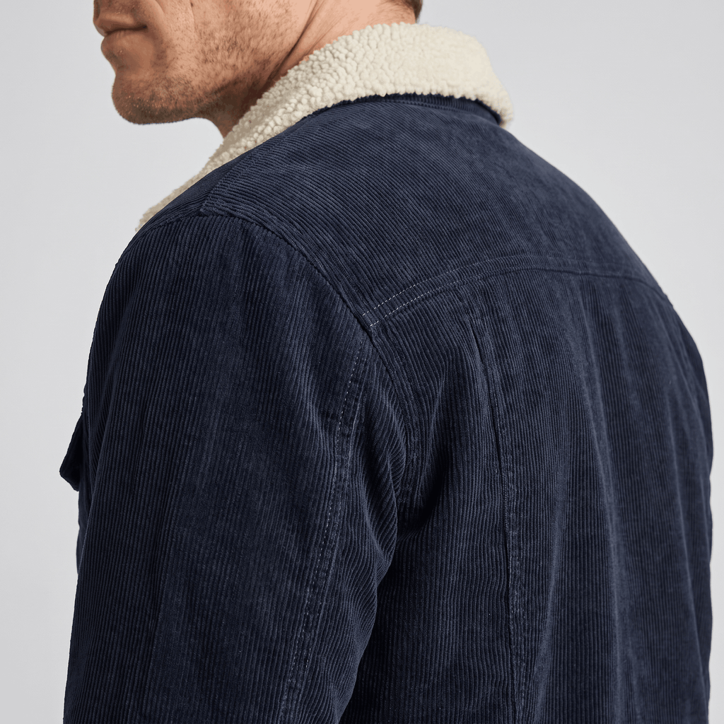 Navy blue cotton corduroy jacket featuring a cream sherpa turn-down collar and structured back yoke detail.