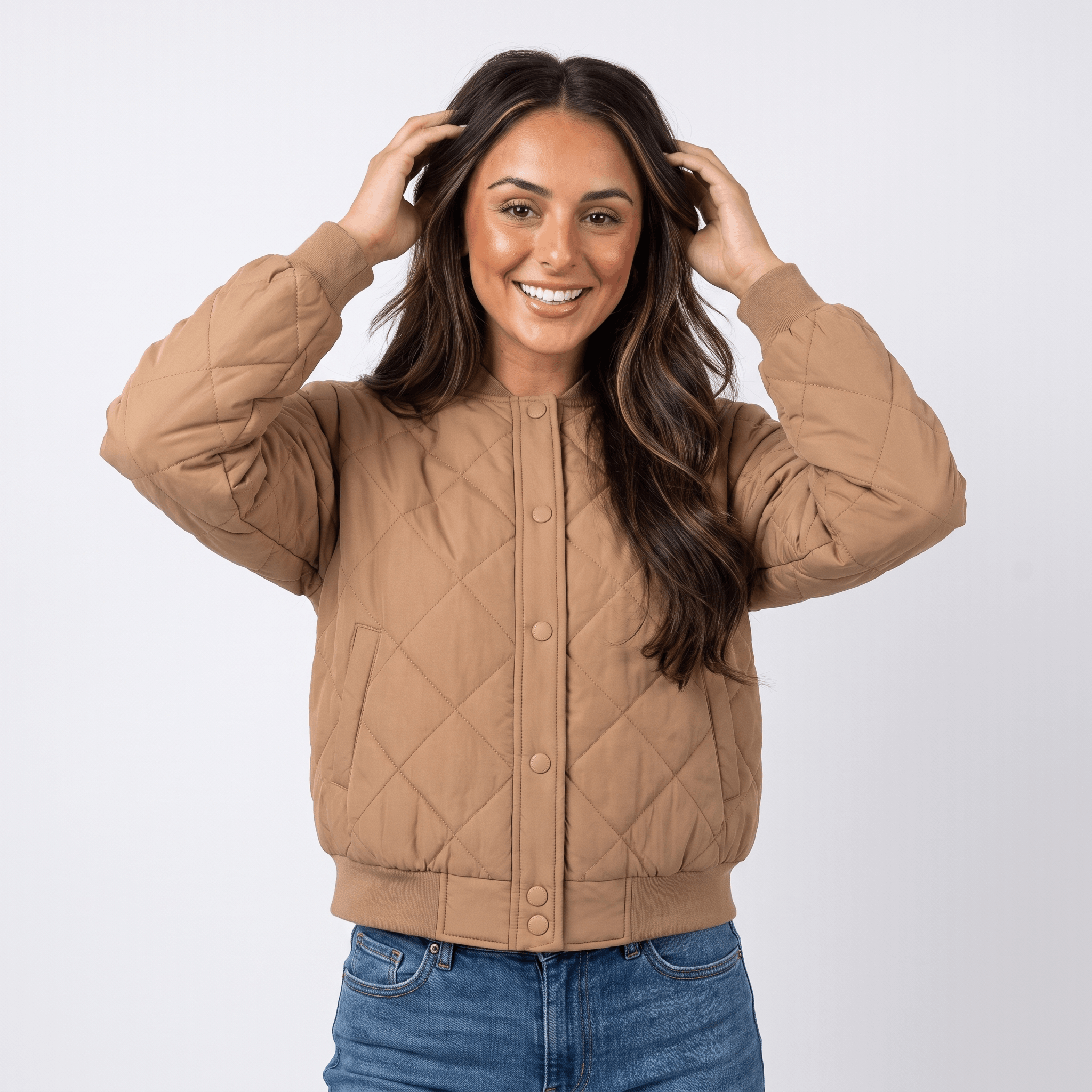 Female model wearing a tan quilted jacket with a stand collar, paired with blue jeans.