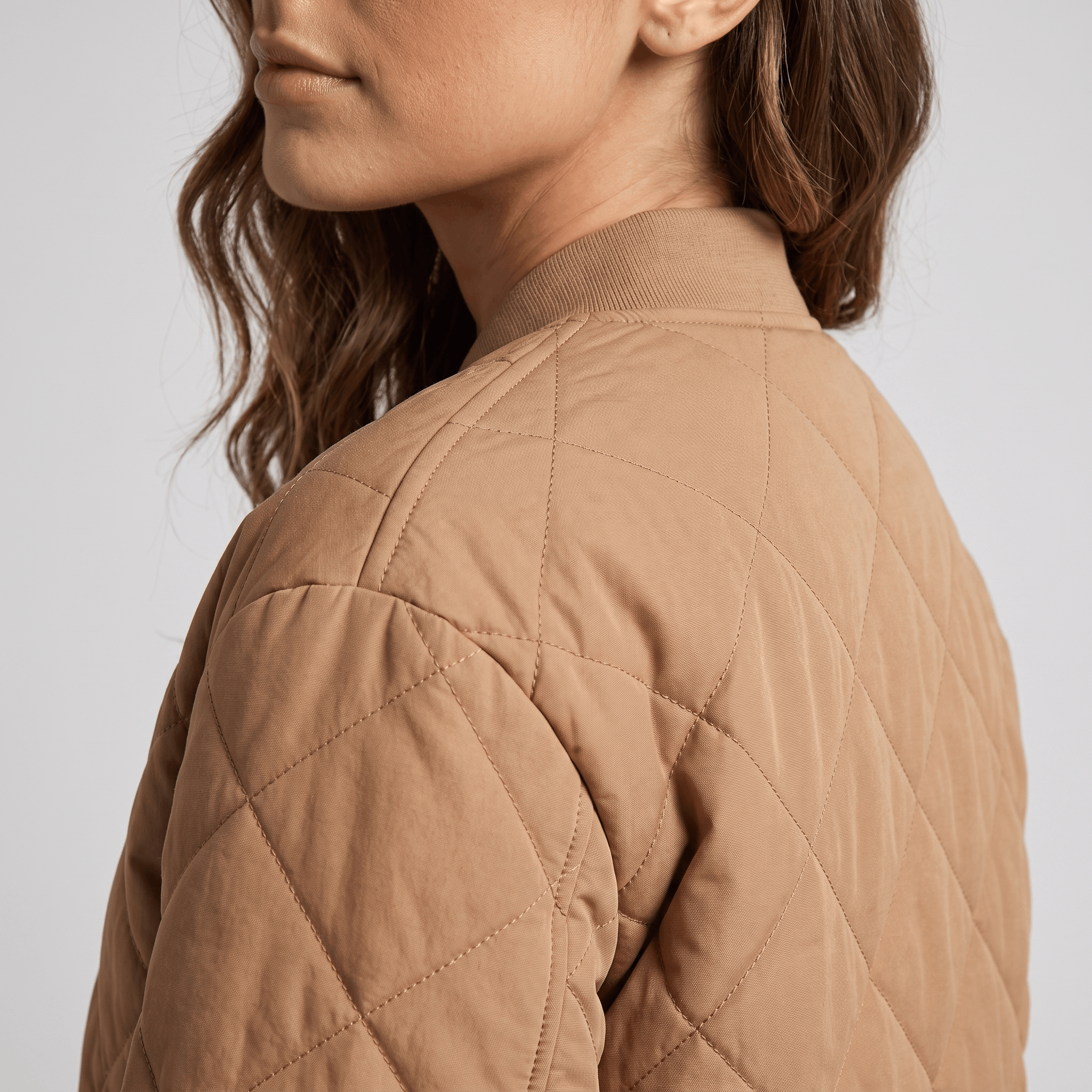 Side and back view of the tan quilted jacket, highlighting the diamond quilting and shoulder.