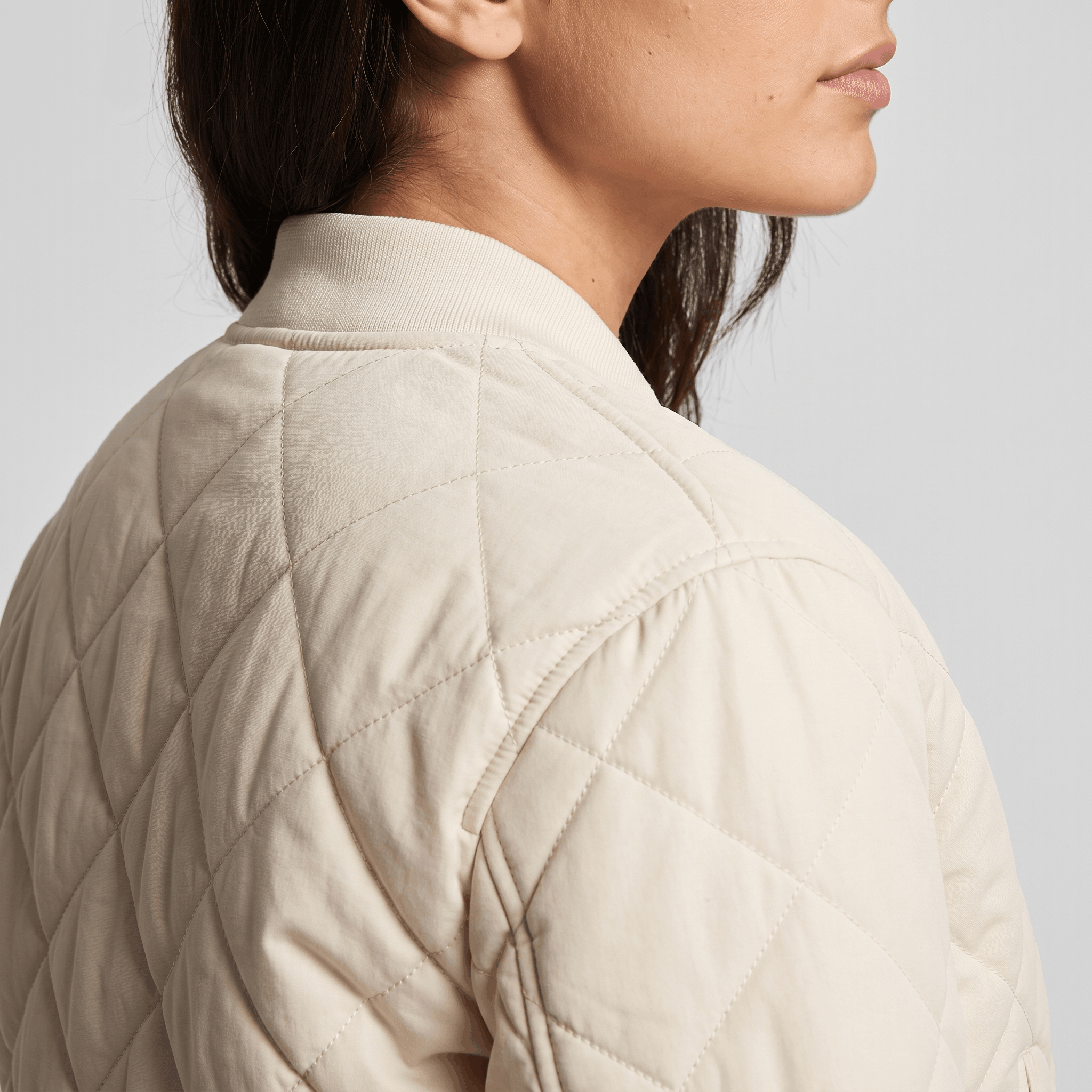 Side and back view of the cream quilted jacket, highlighting the diamond quilting and collar.