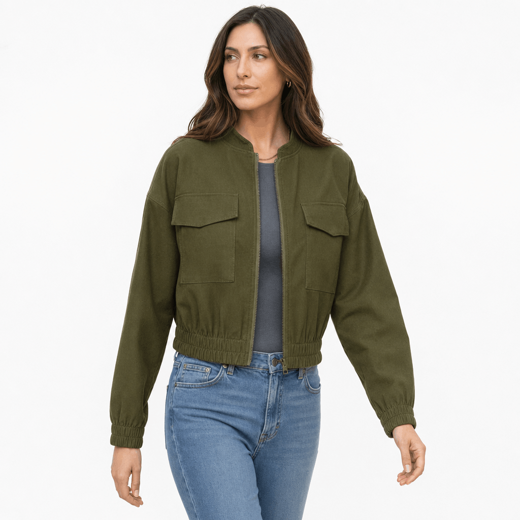 Female model wearing an olive green cropped utility jacket with buttoned chest pockets and blue jeans.