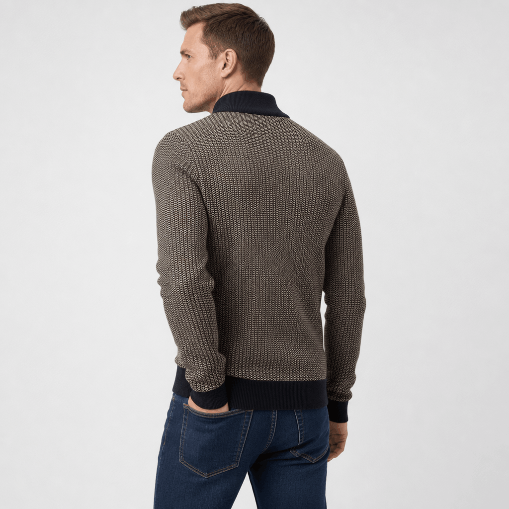 Back view of the man wearing the dark gray textured half-zip sweater with blue jeans.
