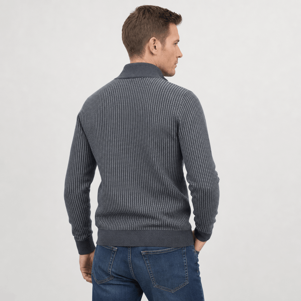 Back view of the man wearing the medium gray textured half-zip sweater with blue jeans.