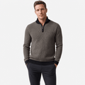 Man wearing a dark gray textured half-zip sweater with black pants, shown in a relaxed front-facing pose.