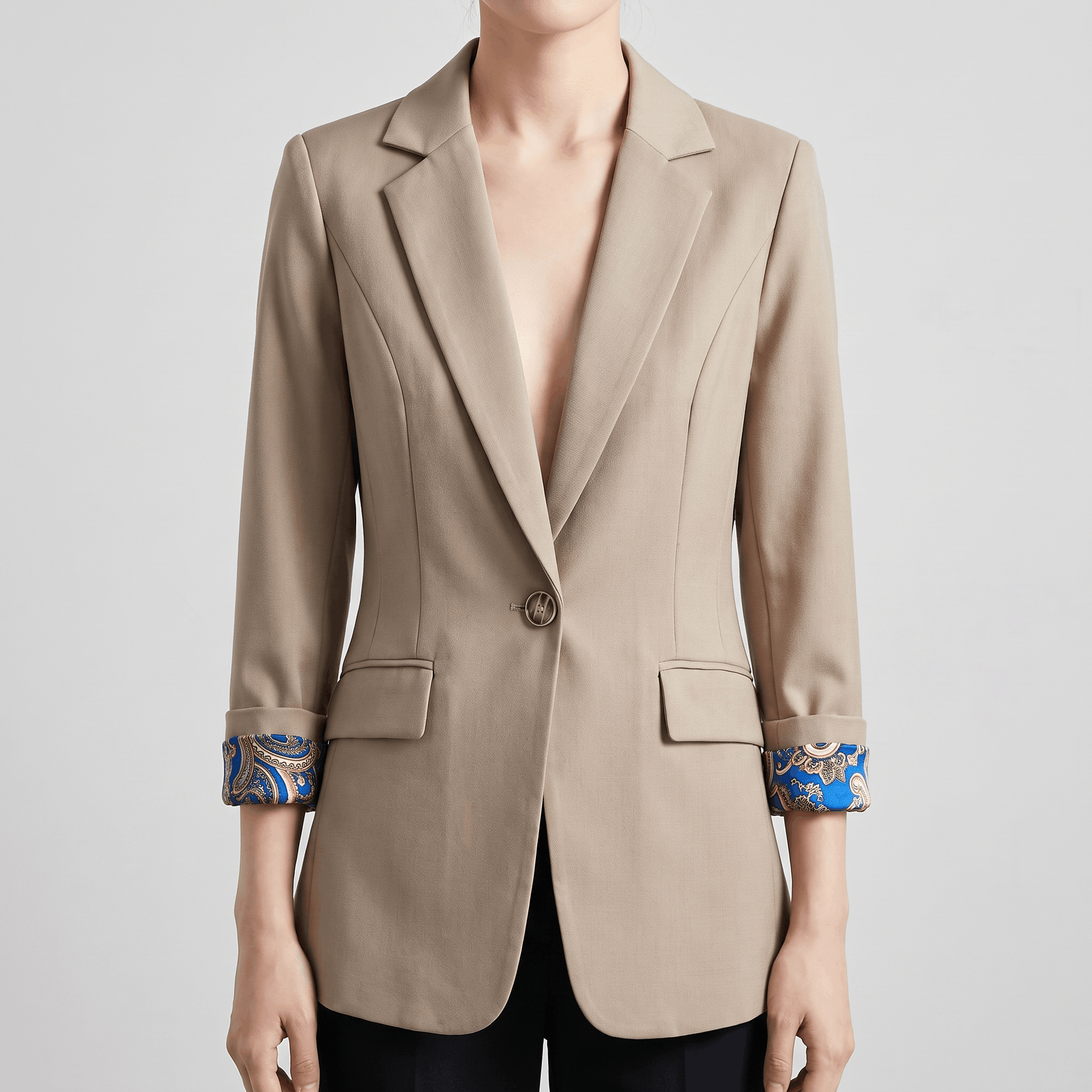 Close-up of the beige blazer showing the lapels, button closure, and patterned shirt cuffs.