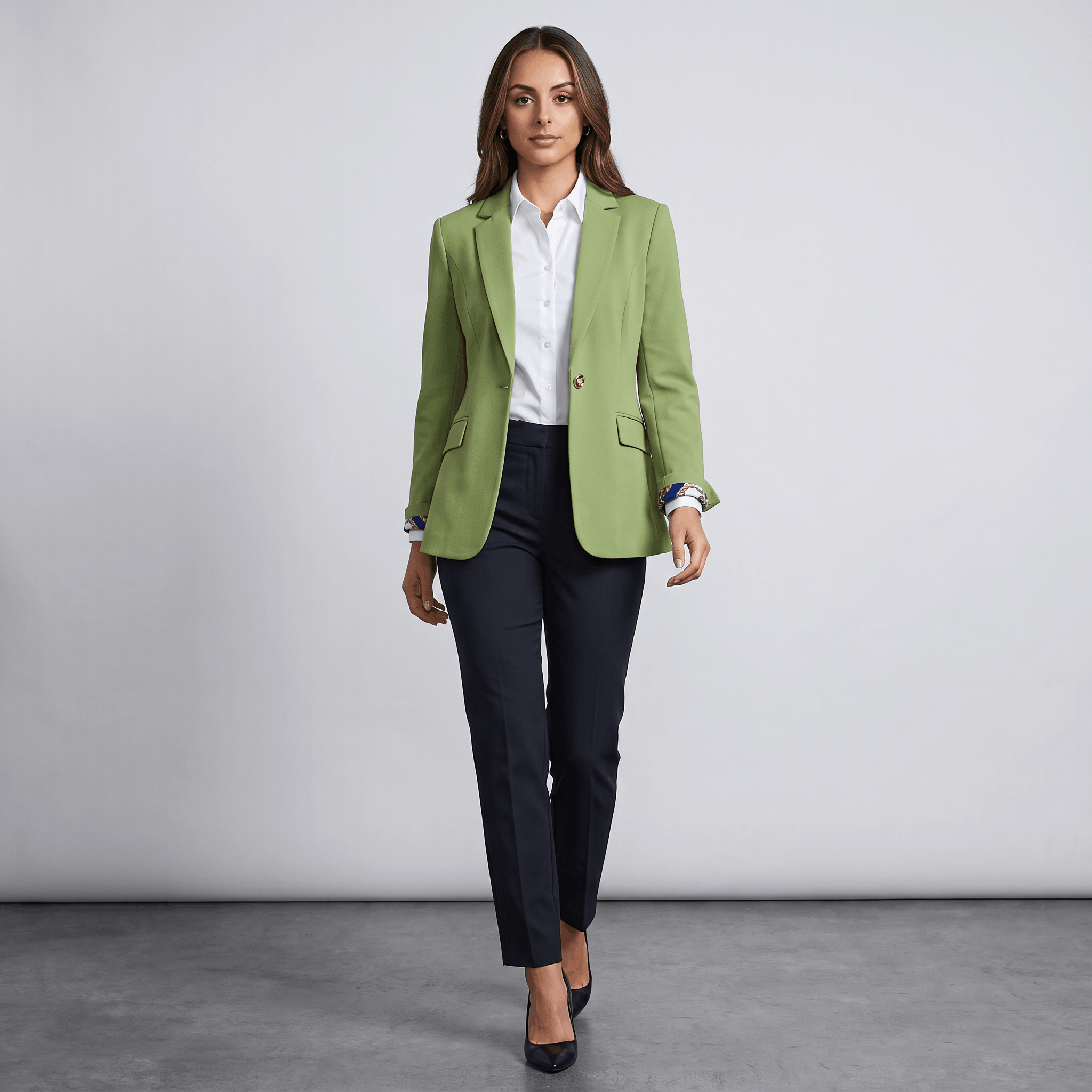 Female model wearing the light green blazer with a light-colored top and dark trousers.