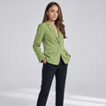 Female model wearing a light green tailored blazer with notched lapels, a single-button closure, flap pockets, and dark trousers.
