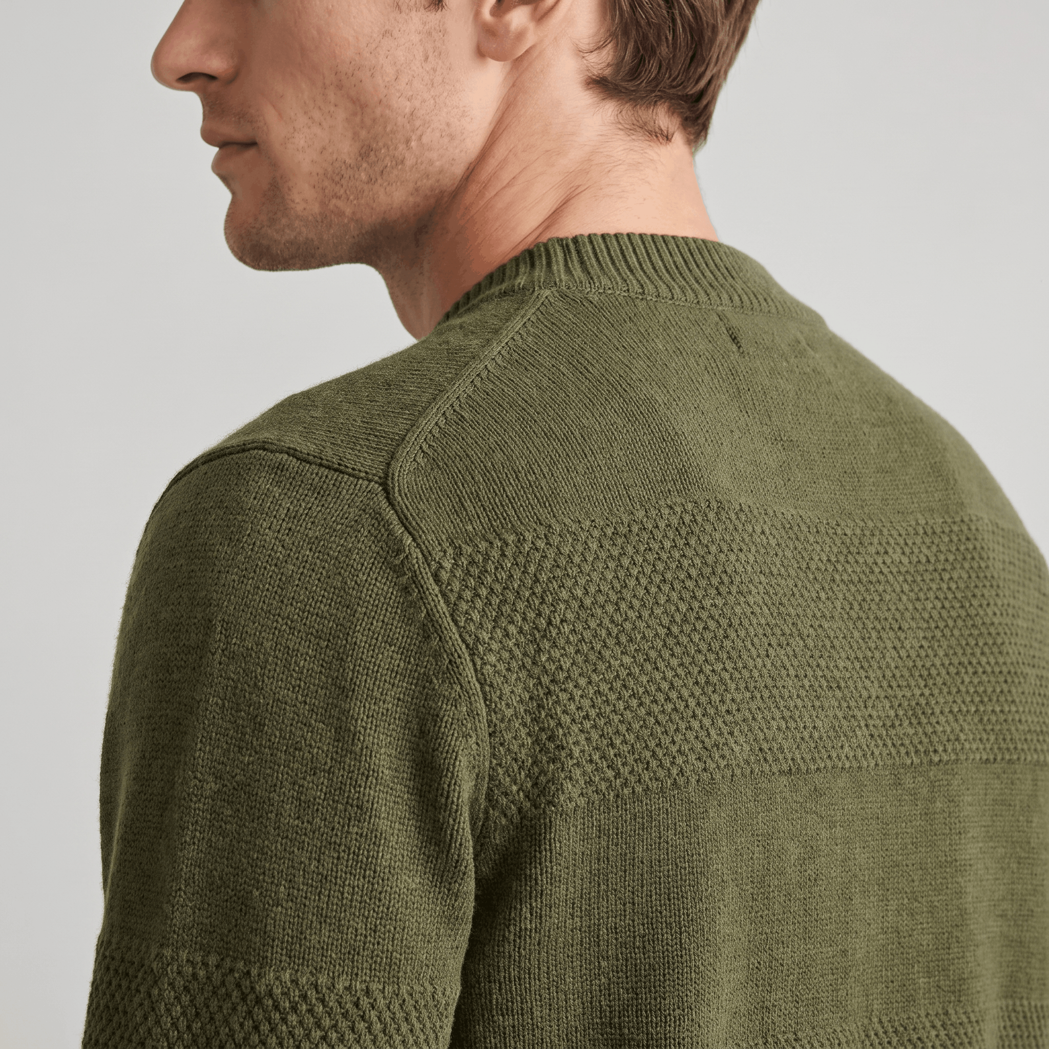 Olive green chunky knit henley sweater featuring alternating smooth and raised textured stripes with a ribbed crew neckline.