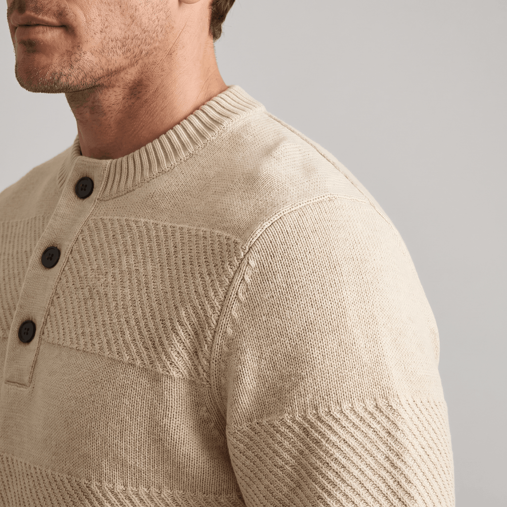 Beige chunky knit henley sweater featuring alternating smooth and raised textured stripes and a three-button placket.
