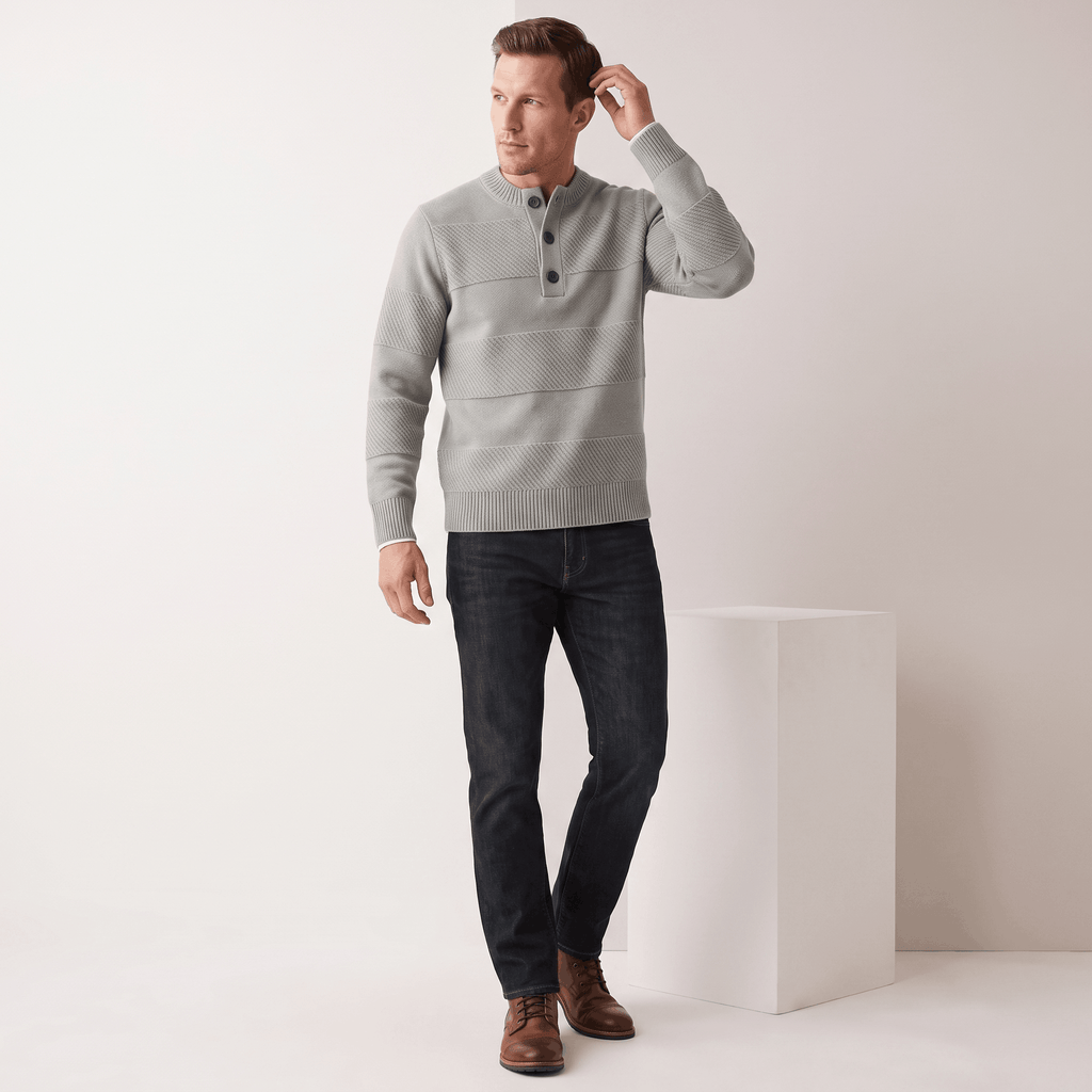 Grey chunky knit henley sweater with textured horizontal stripes, three-button placket, and ribbed trim, worn with dark jeans.