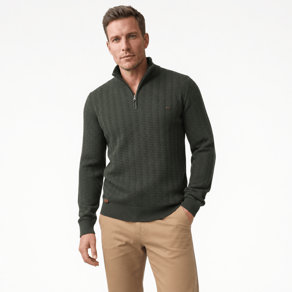 Man wearing a dark olive green textured half-zip sweater with beige pants, shown in a relaxed standing pose.