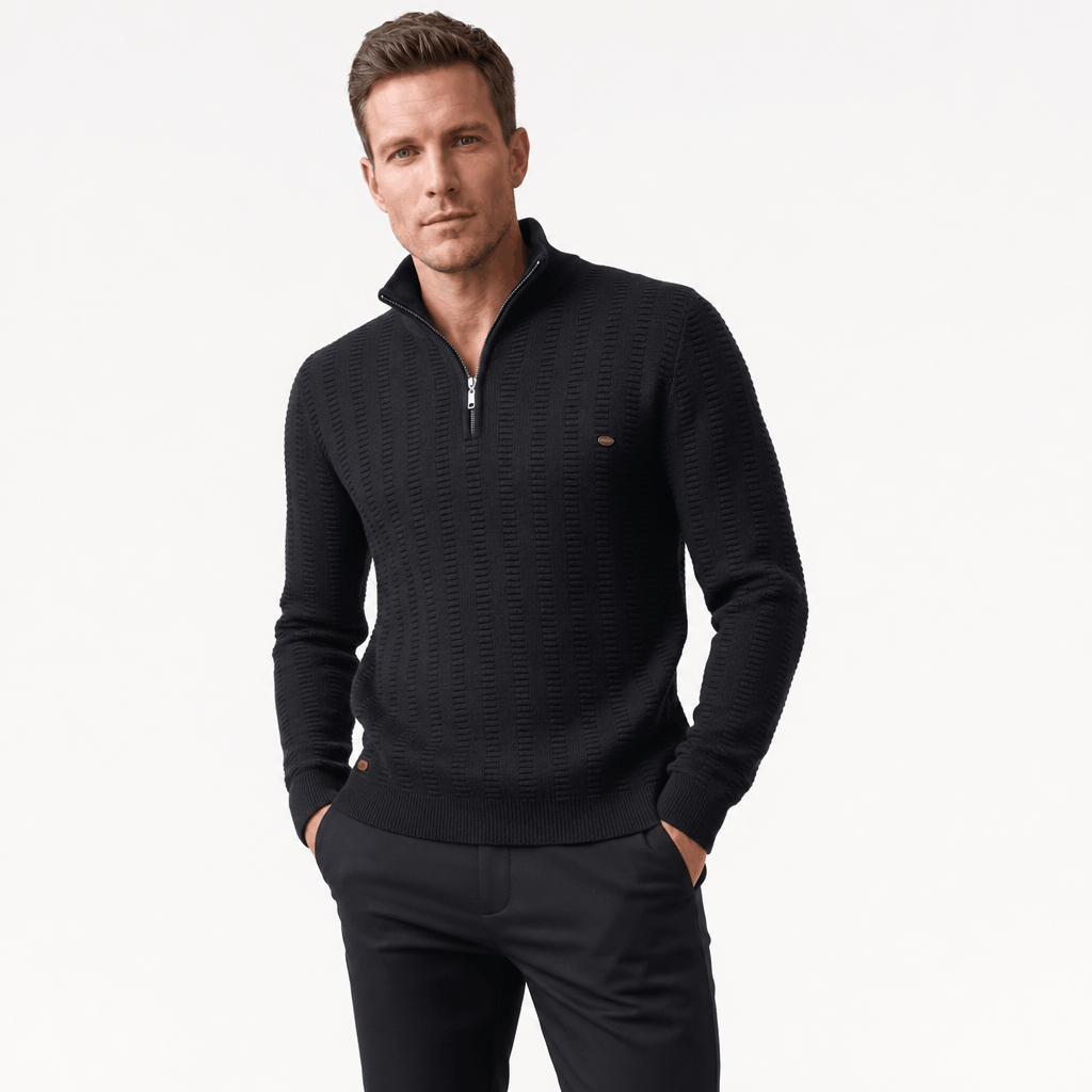 Man wearing a black textured half-zip sweater with black pants, shown in a relaxed standing pose.