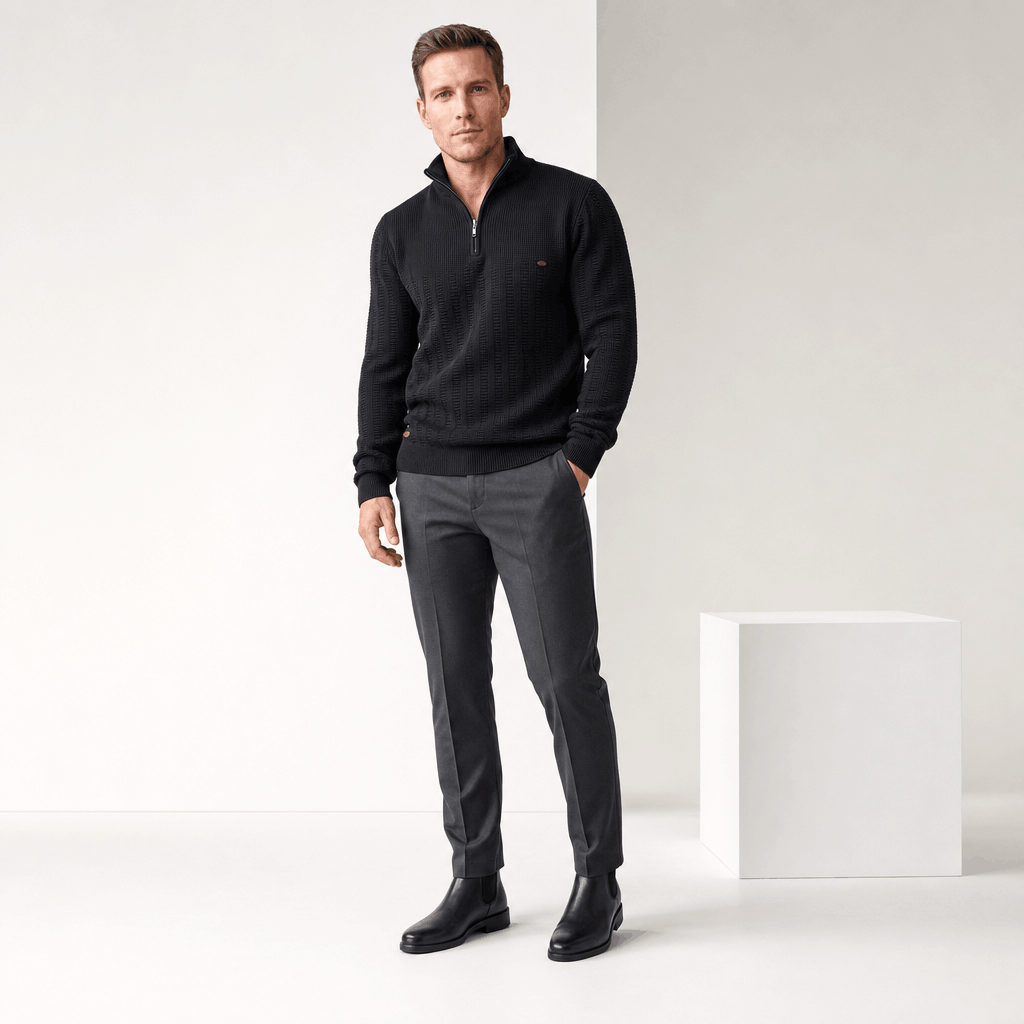 Full-body view of the man wearing the black textured half-zip sweater with dark pants.