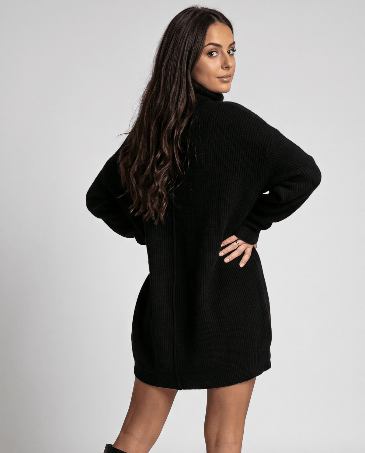 Black Oversized Longline Sweater worn by a female model, featuring a slouchy fit, high turtleneck collar, long sleeves, soft knit texture, and extended hem.