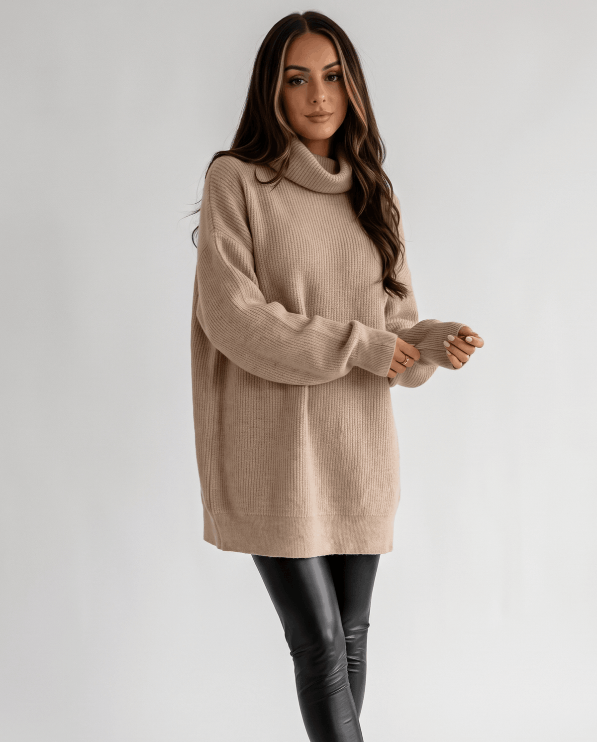 Beige Oversized Longline Sweater worn by a female model, featuring a slouchy fit, high turtleneck collar, long sleeves, and soft knit texture.