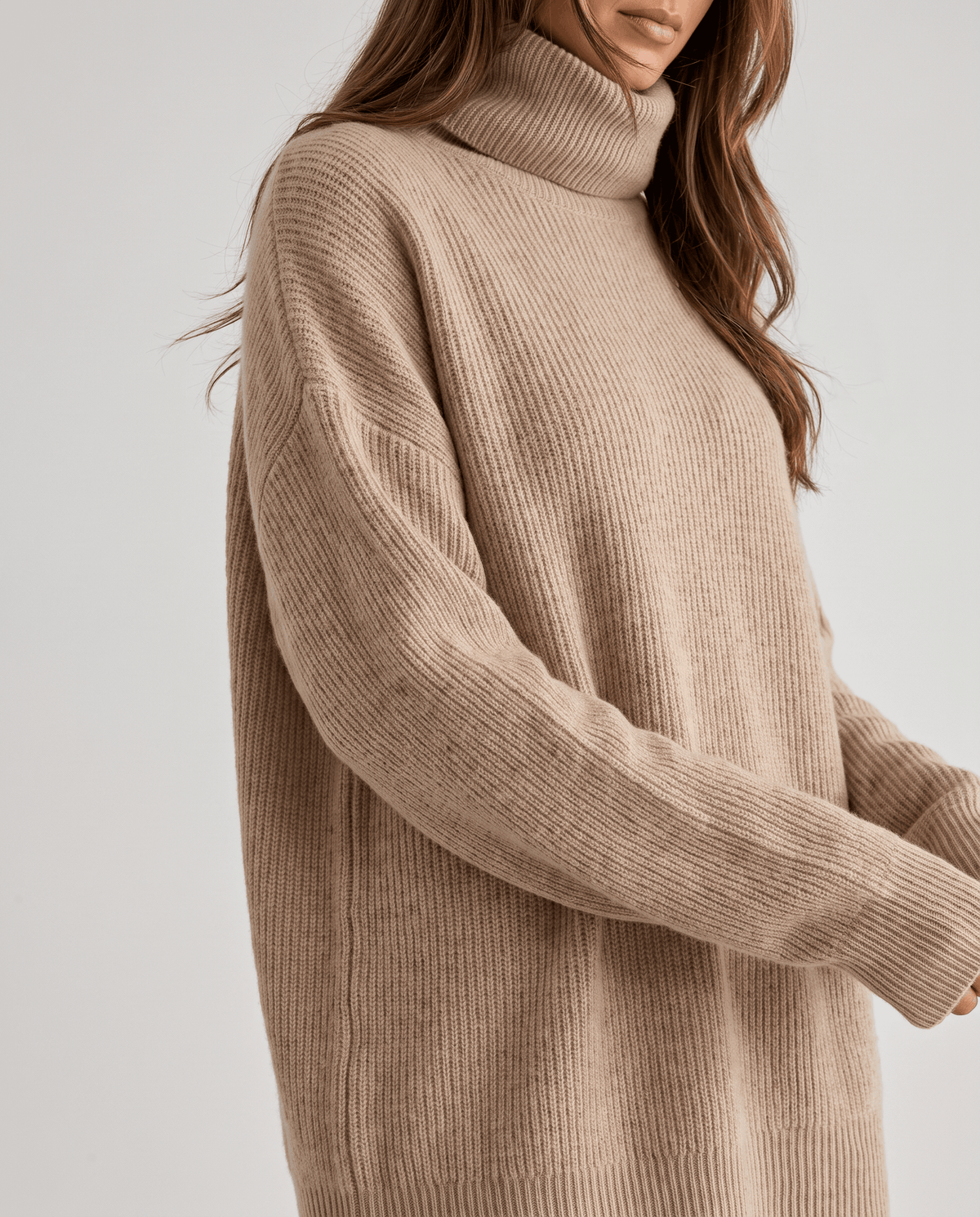 Close-up of the beige Oversized Longline Sweater worn by a female model, highlighting the soft knit texture, long sleeve, and relaxed fit.
