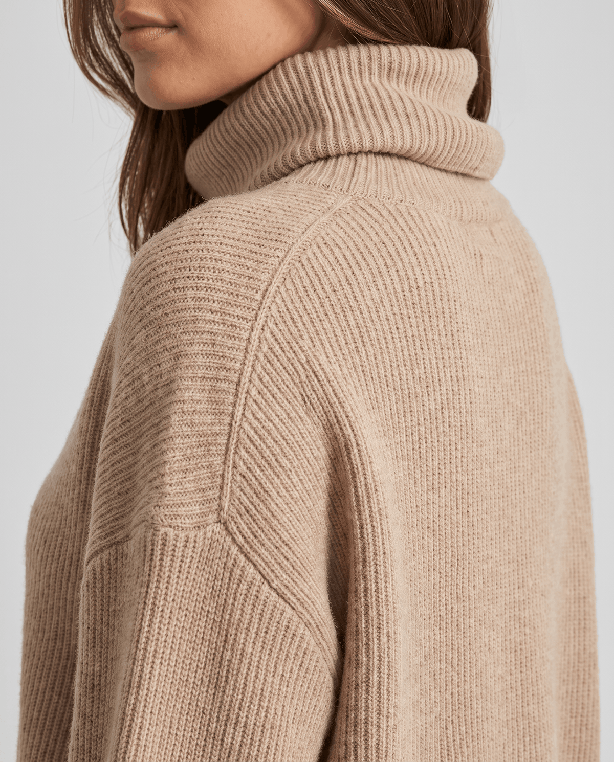 Close-up of the beige Oversized Longline Sweater worn by a female model, showing the high turtleneck collar and soft knit texture.
