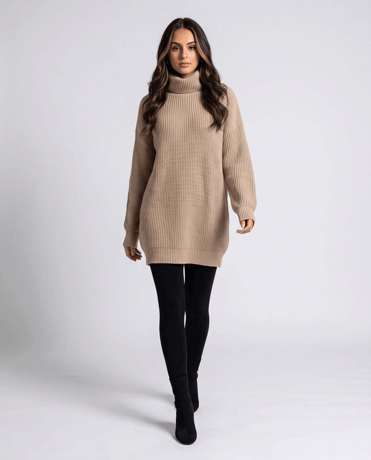Beige Oversized Longline Sweater worn by a female model, featuring a slouchy fit, high turtleneck collar, long sleeves, and longline silhouette.