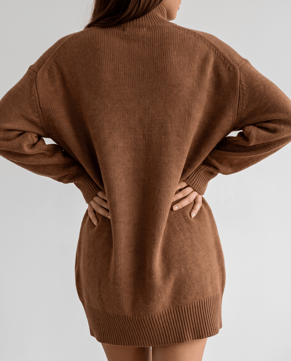 Brown Oversized Longline Sweater worn by a female model from the back, showcasing the relaxed slouchy fit, soft knit texture, high collar, and longline silhouette.
