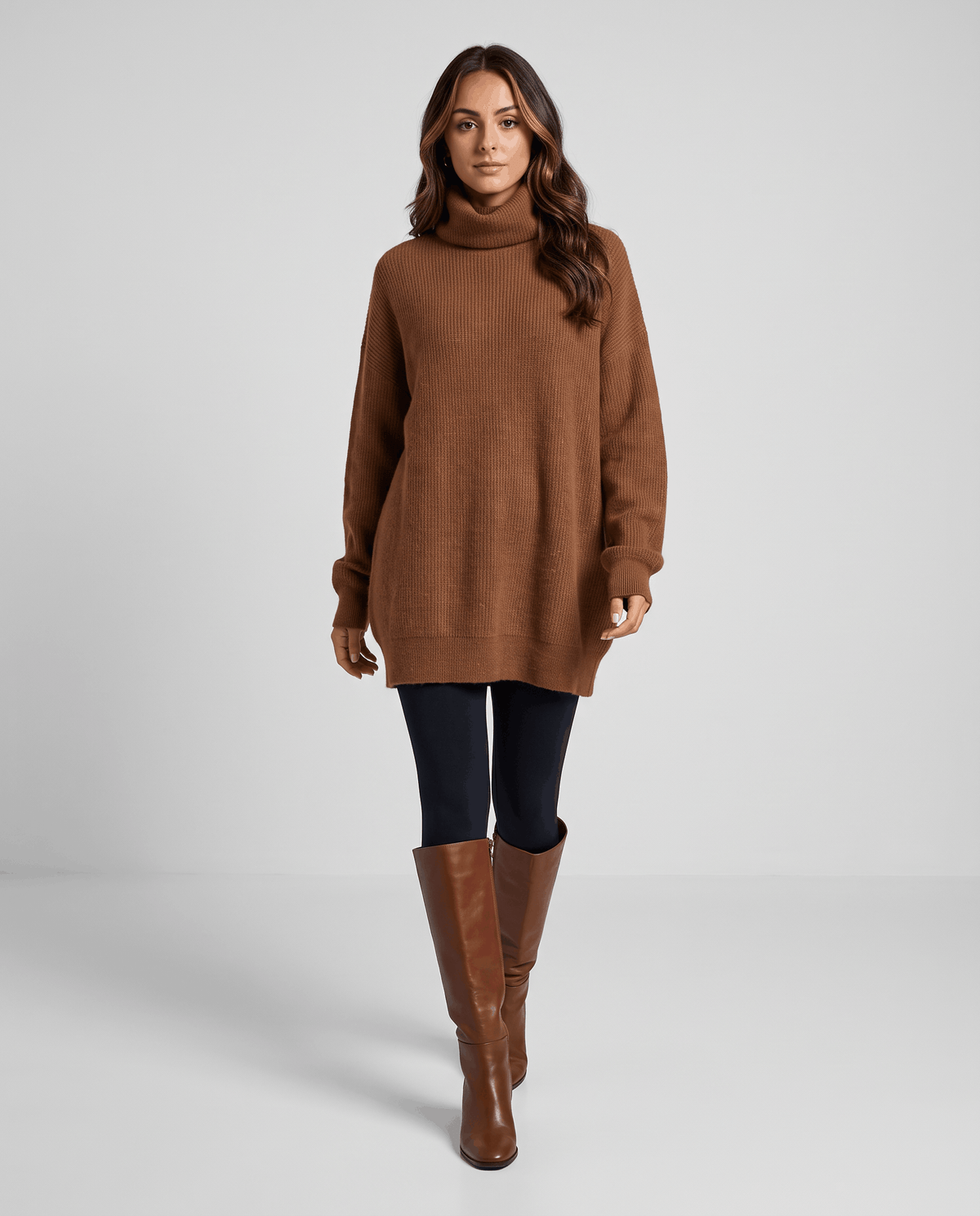 Brown Oversized Longline Sweater worn by a female model with black leggings, featuring a slouchy oversized fit, high turtleneck collar, long sleeves, and longline hem.