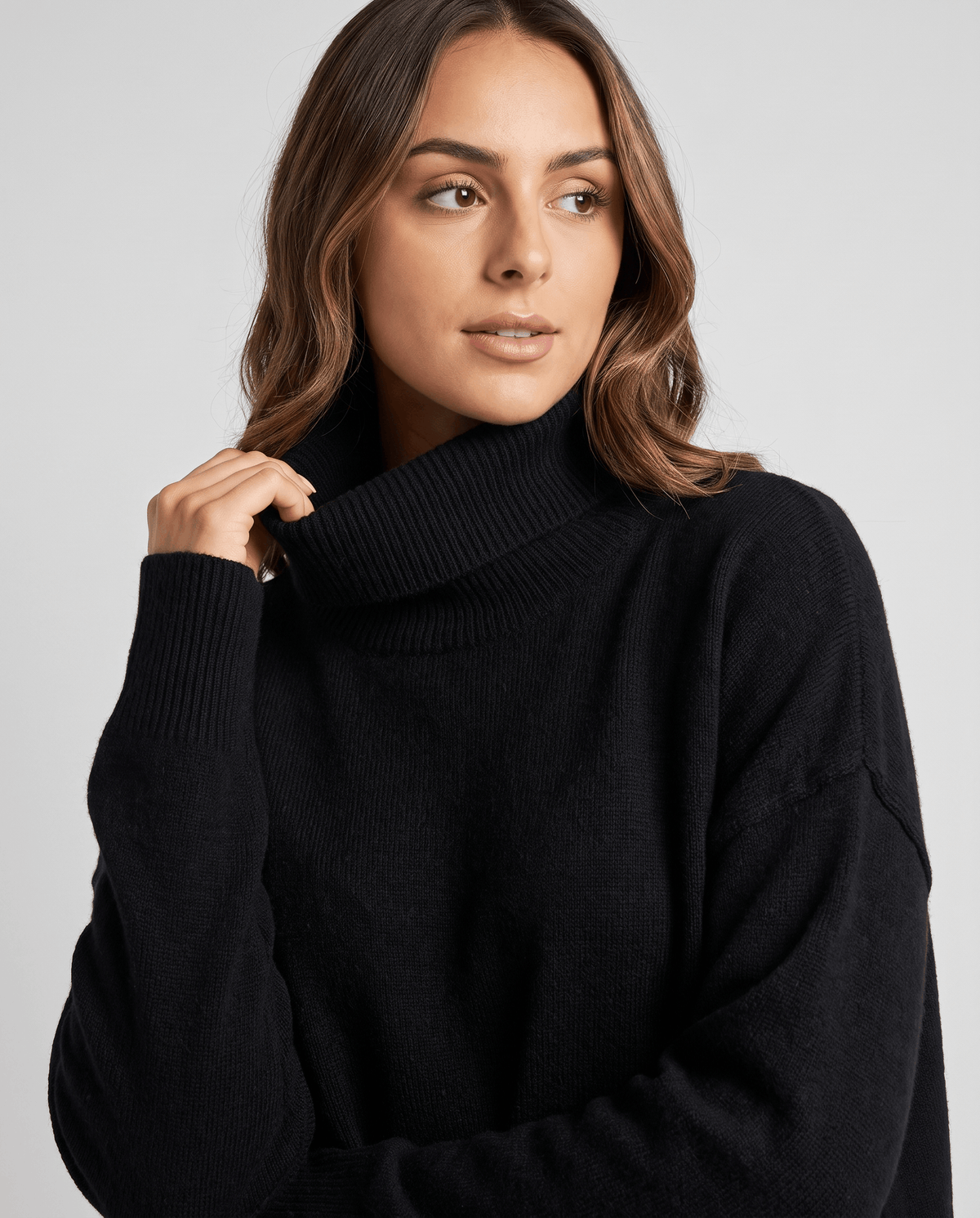 Black Oversized Longline Sweater worn by a female model, shown from the front with a relaxed slouchy fit, high turtleneck collar, and long sleeves.