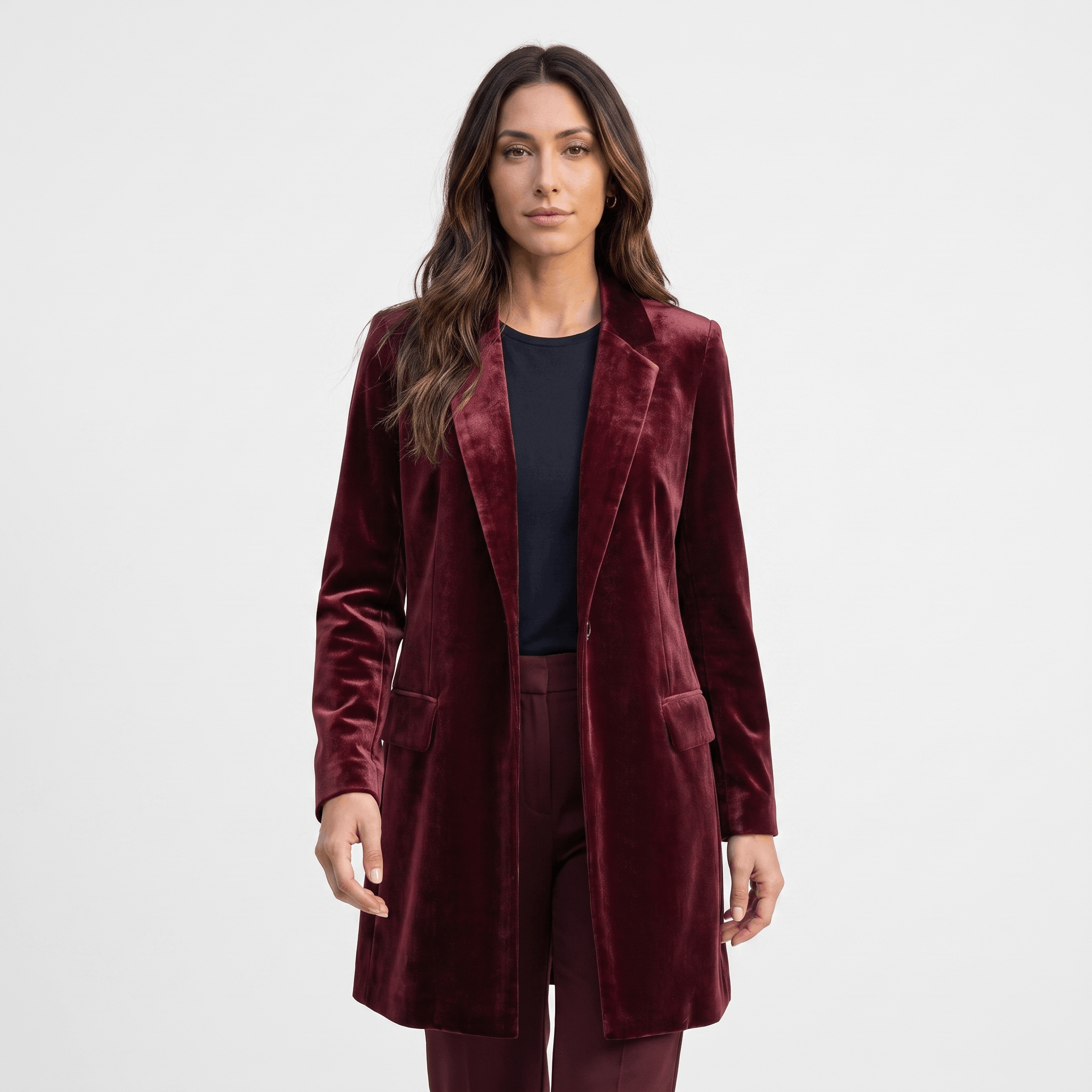 Female model wearing a burgundy velvet blazer with notched lapels and a single-button closure.