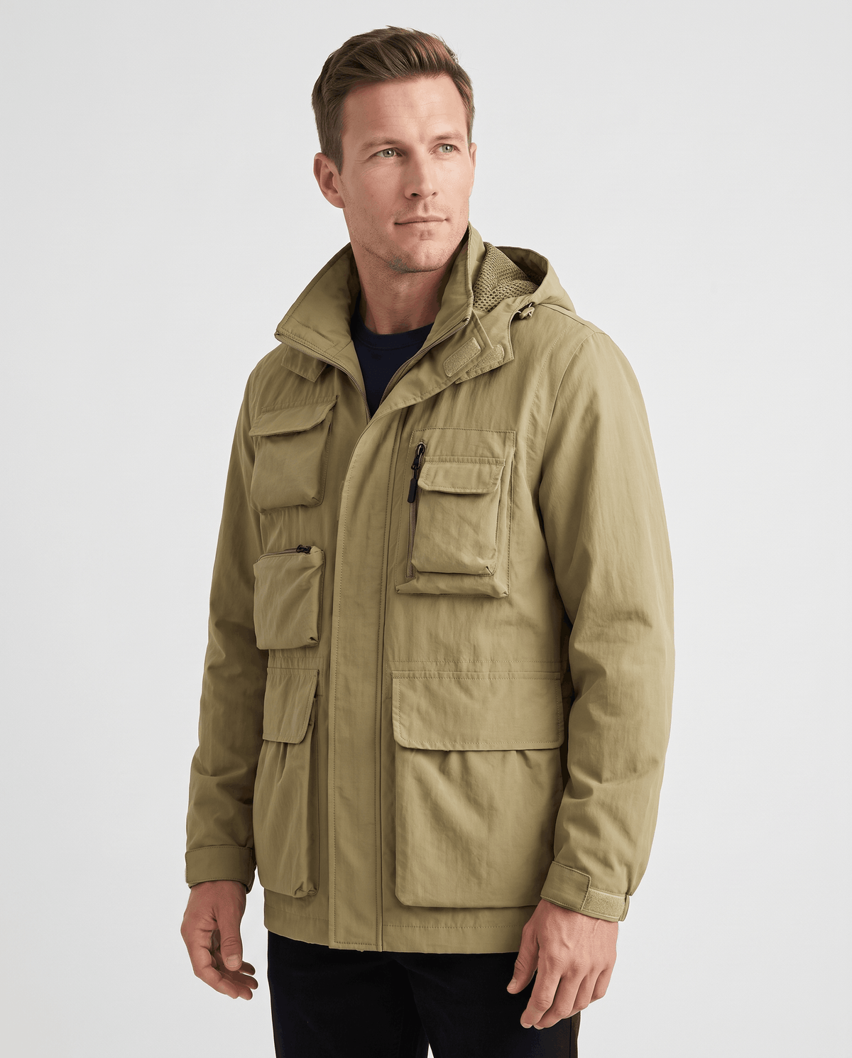 A man wearing a khaki parka jacket with warm padded lining, a hood, and multiple front pockets