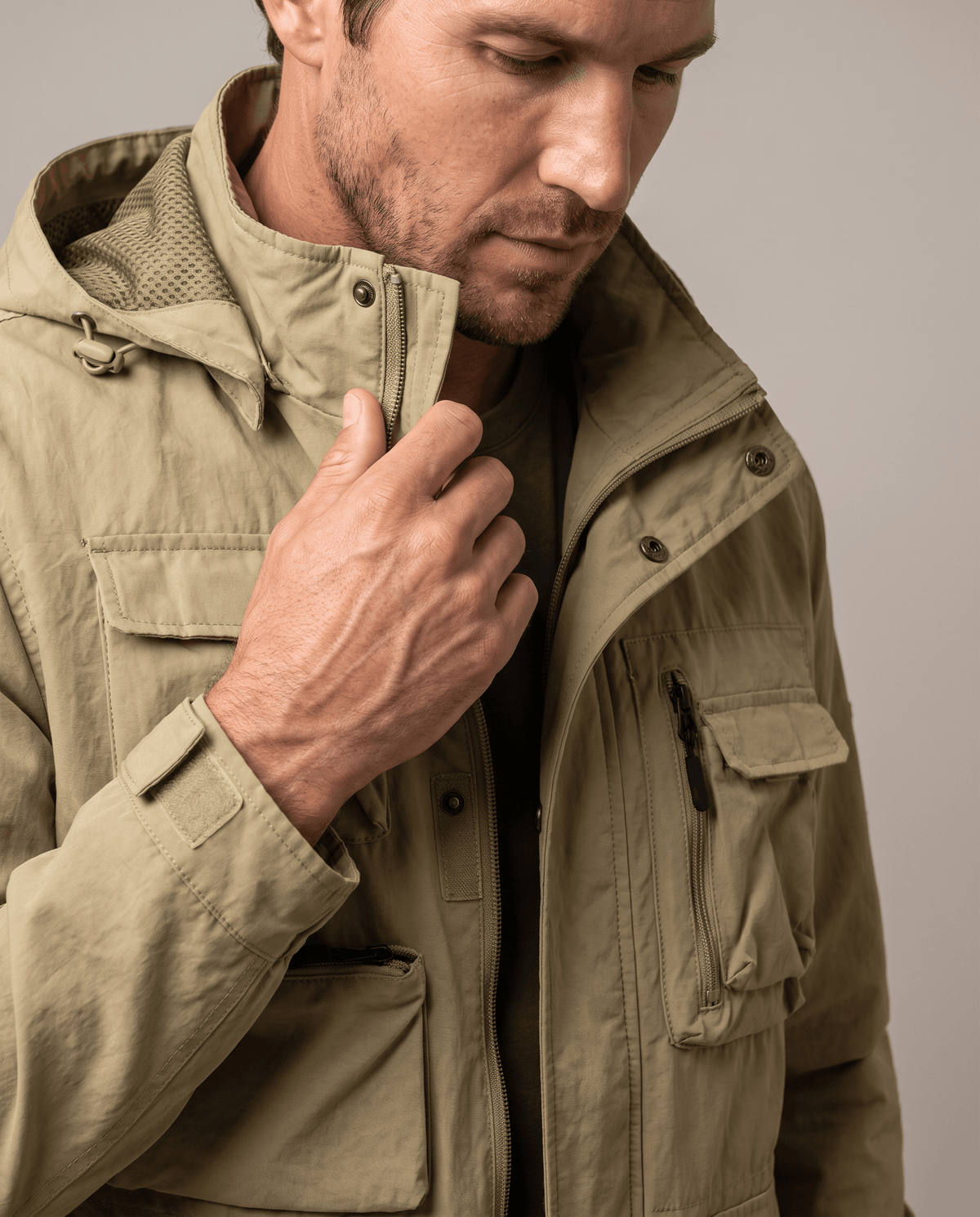 Close-up of a man wearing a khaki parka jacket, showing the hood, warm padded lining, and front pocket details