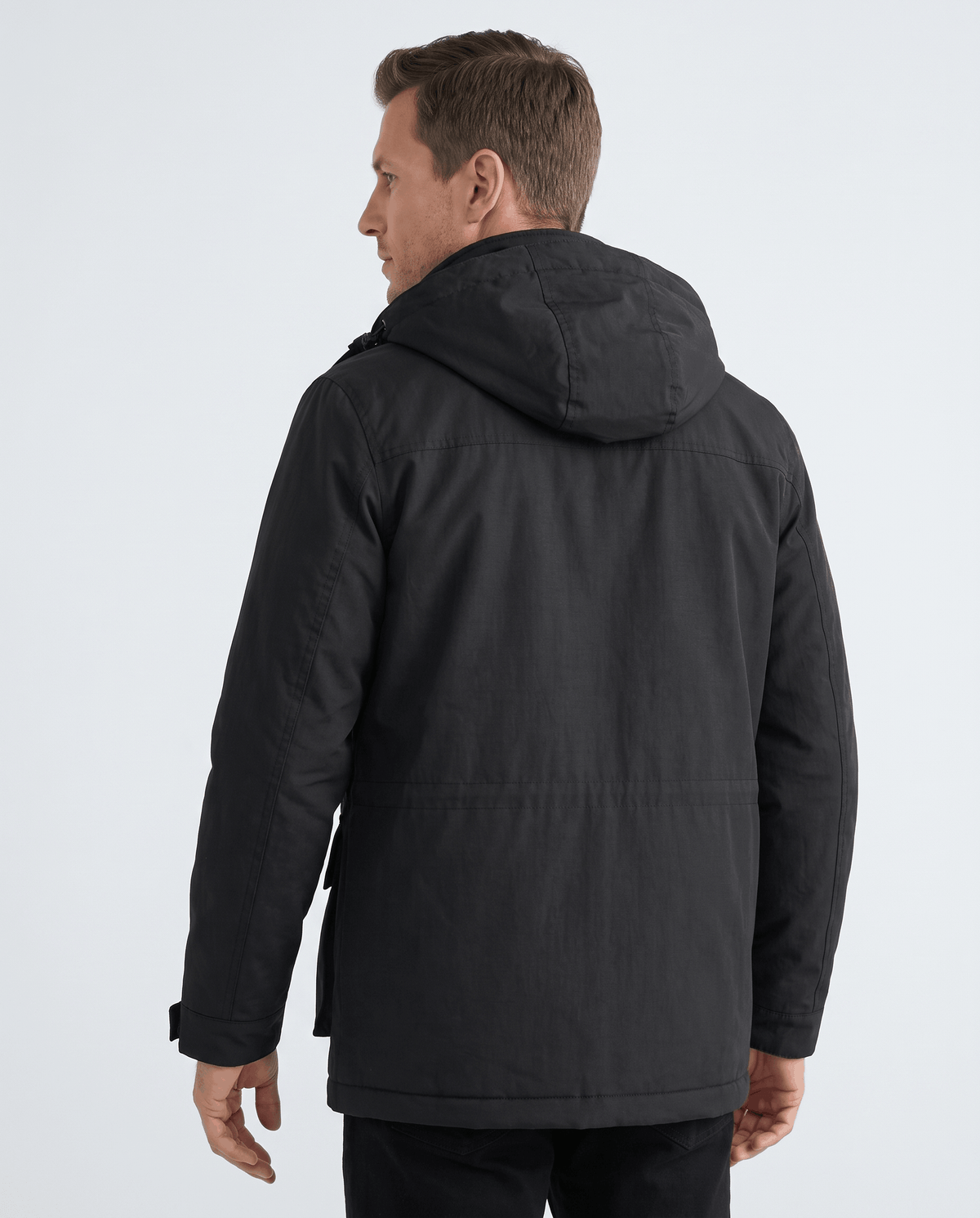 A man wearing a black hooded parka jacket with warm padded lining and a multi-pocket design, shown from the back