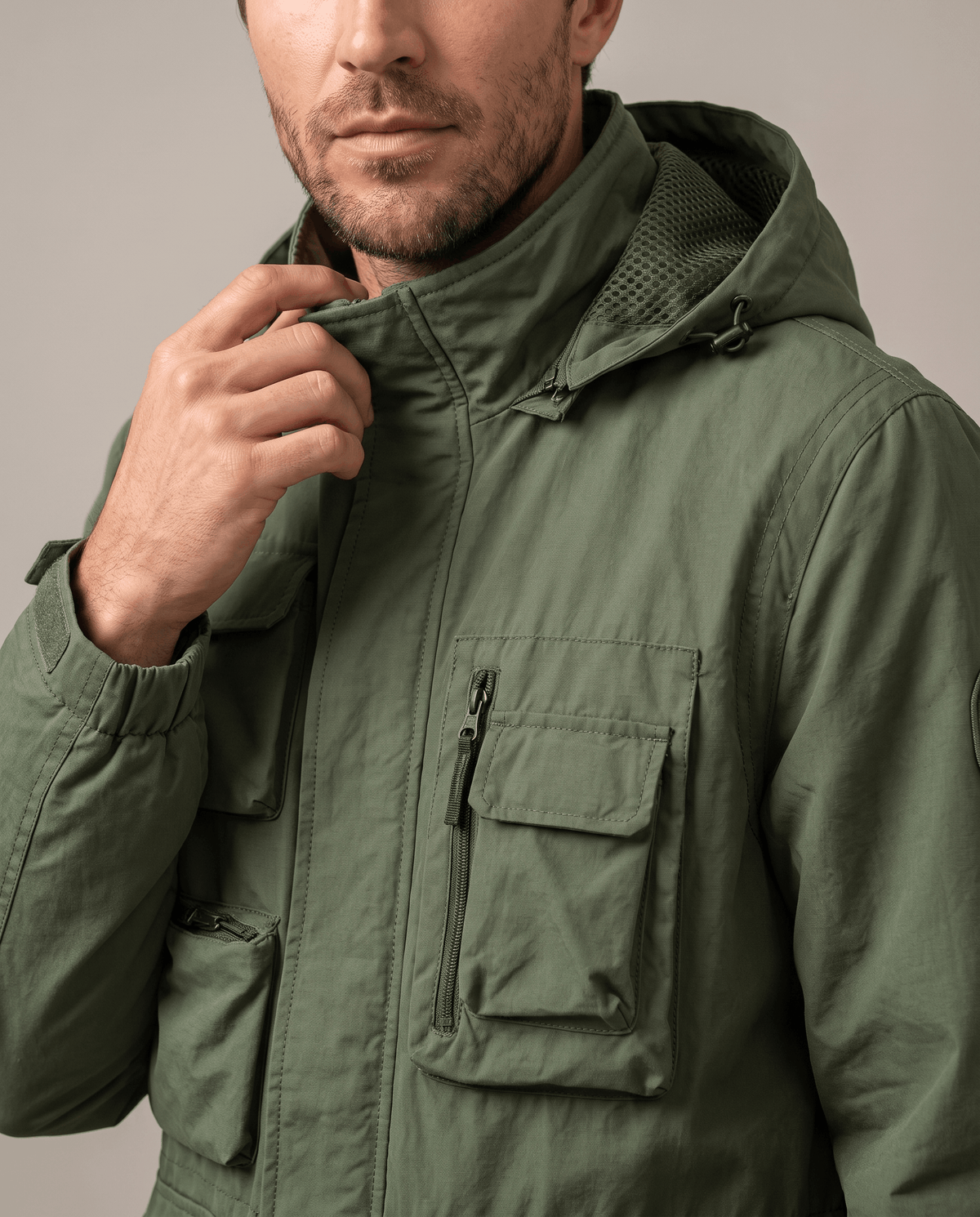 Close-up of a man wearing a green parka jacket, showing the hood, warm padded lining, and front pocket details