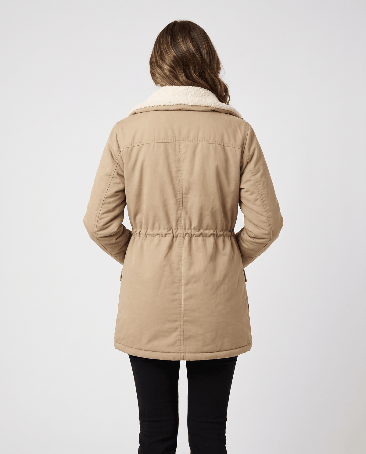 A woman wearing a beige mid-length parka jacket with plush lining and an adjustable waist, shown from the back