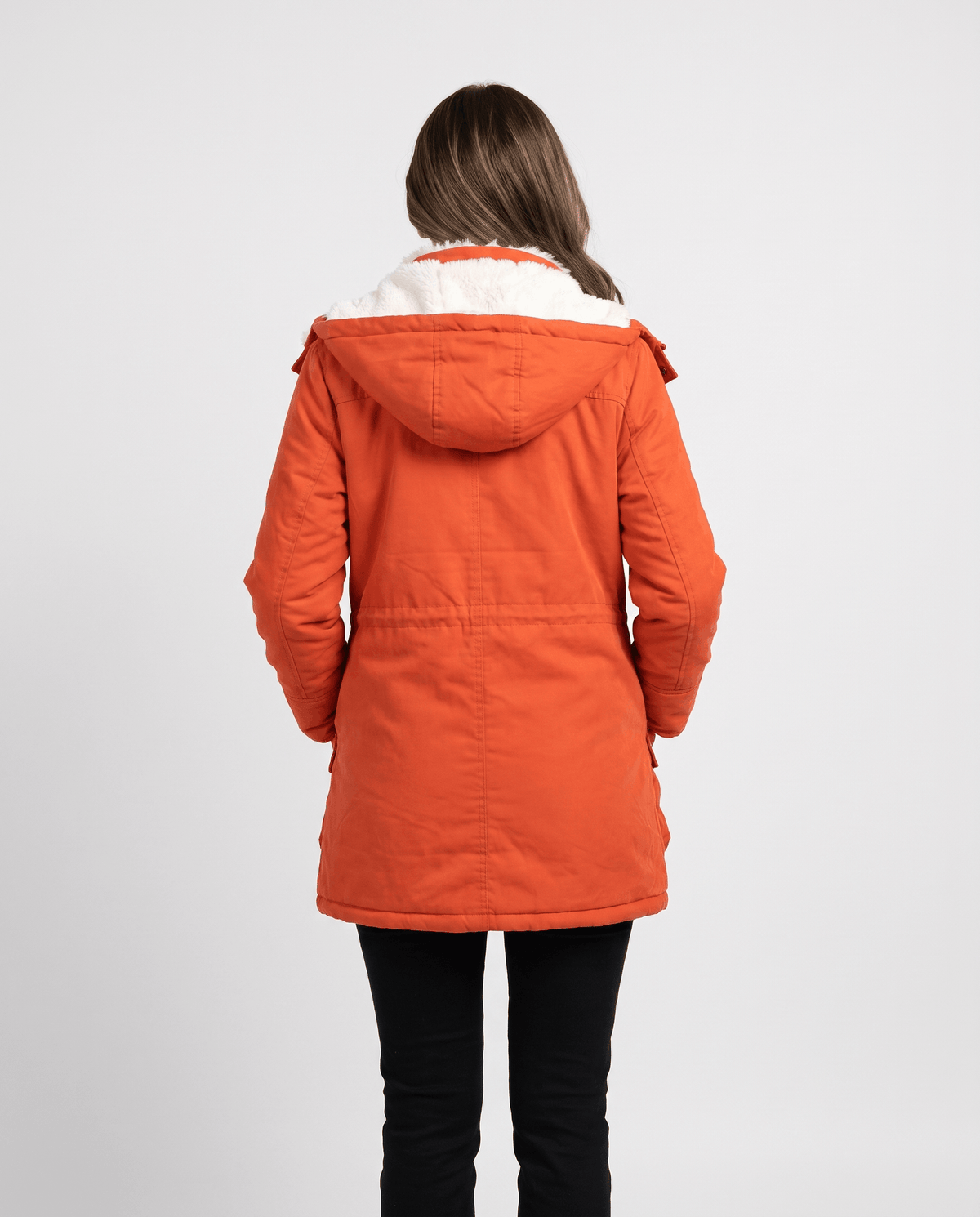 A woman wearing a red mid-length parka jacket with plush lining, a hood, and adjustable waist, shown from the back