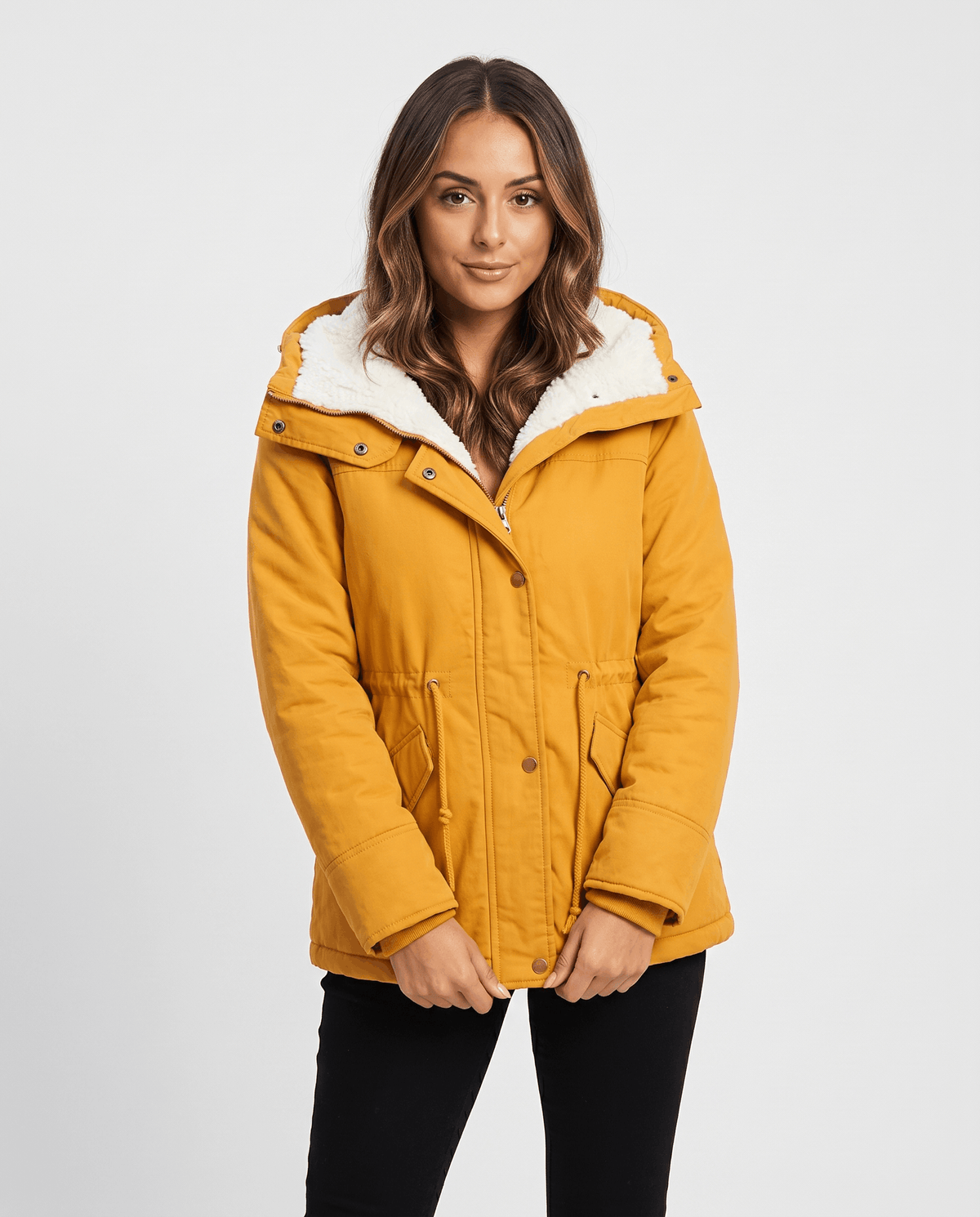 A woman wearing a mustard yellow mid-length parka jacket with plush lining, a hood, and adjustable waist