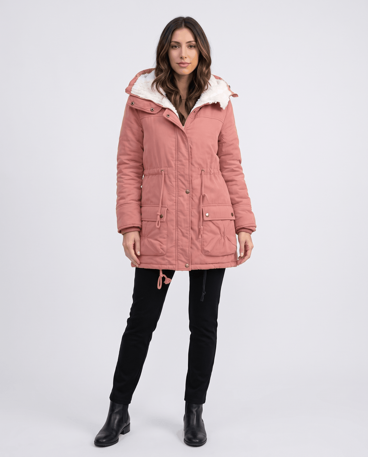 A woman wearing a pink mid-length parka jacket with plush lining, a hood, and adjustable waist, full-body view