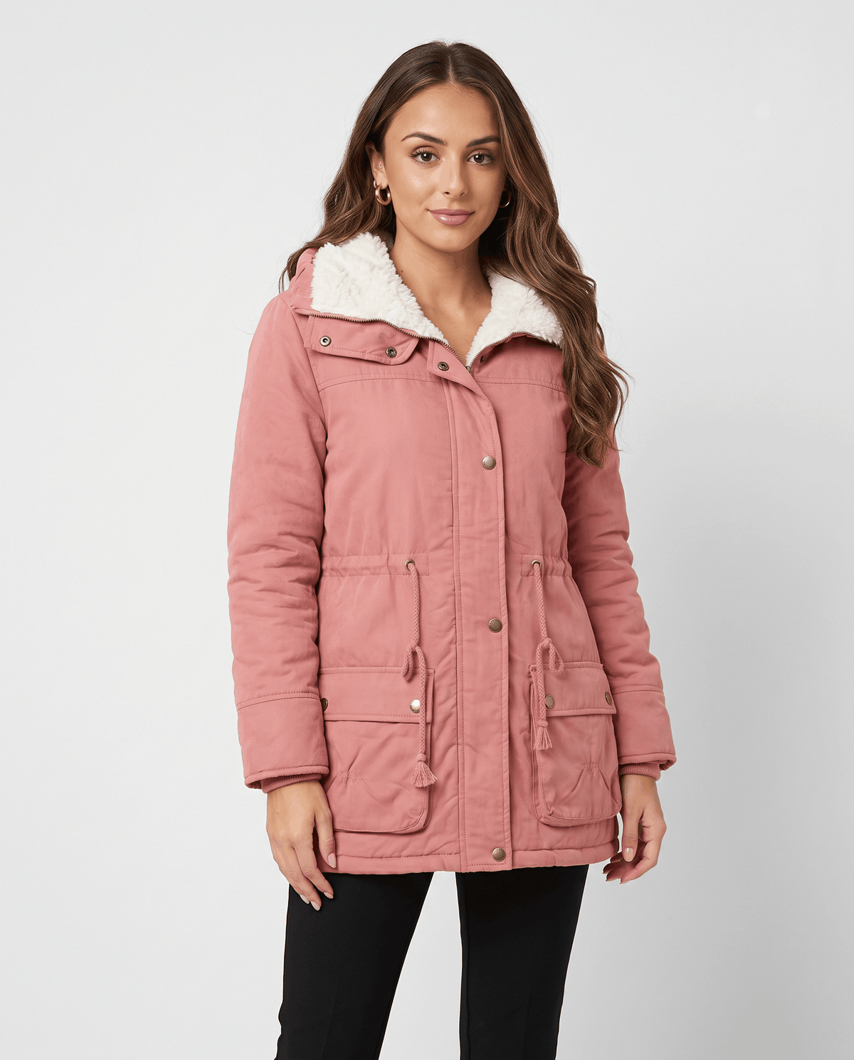 A woman wearing a pink parka jacket with plush lining, a mid-length fit, hood, and adjustable waist