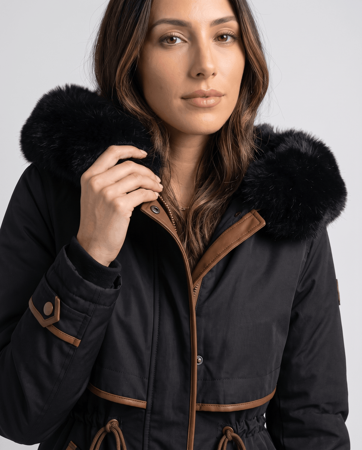 Close-up of a woman wearing a black winter parka with a plush fur-trimmed hood and adjustable waist