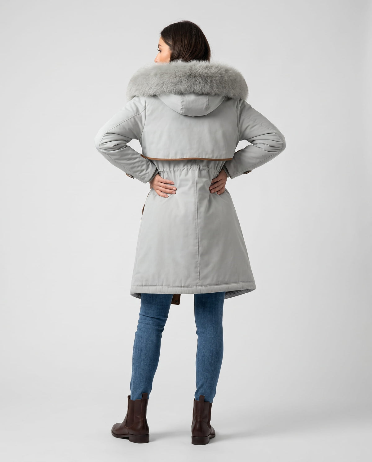A woman wearing a white winter parka with a plush fur-trimmed hood and adjustable waist, shown from the back