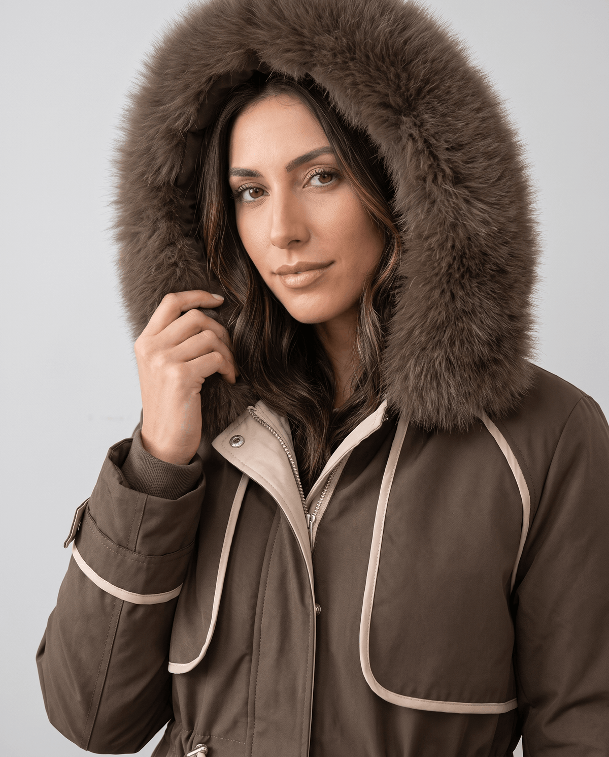 Close-up of a woman wearing a brown winter parka, showing the plush fur-trimmed hood and cozy lining