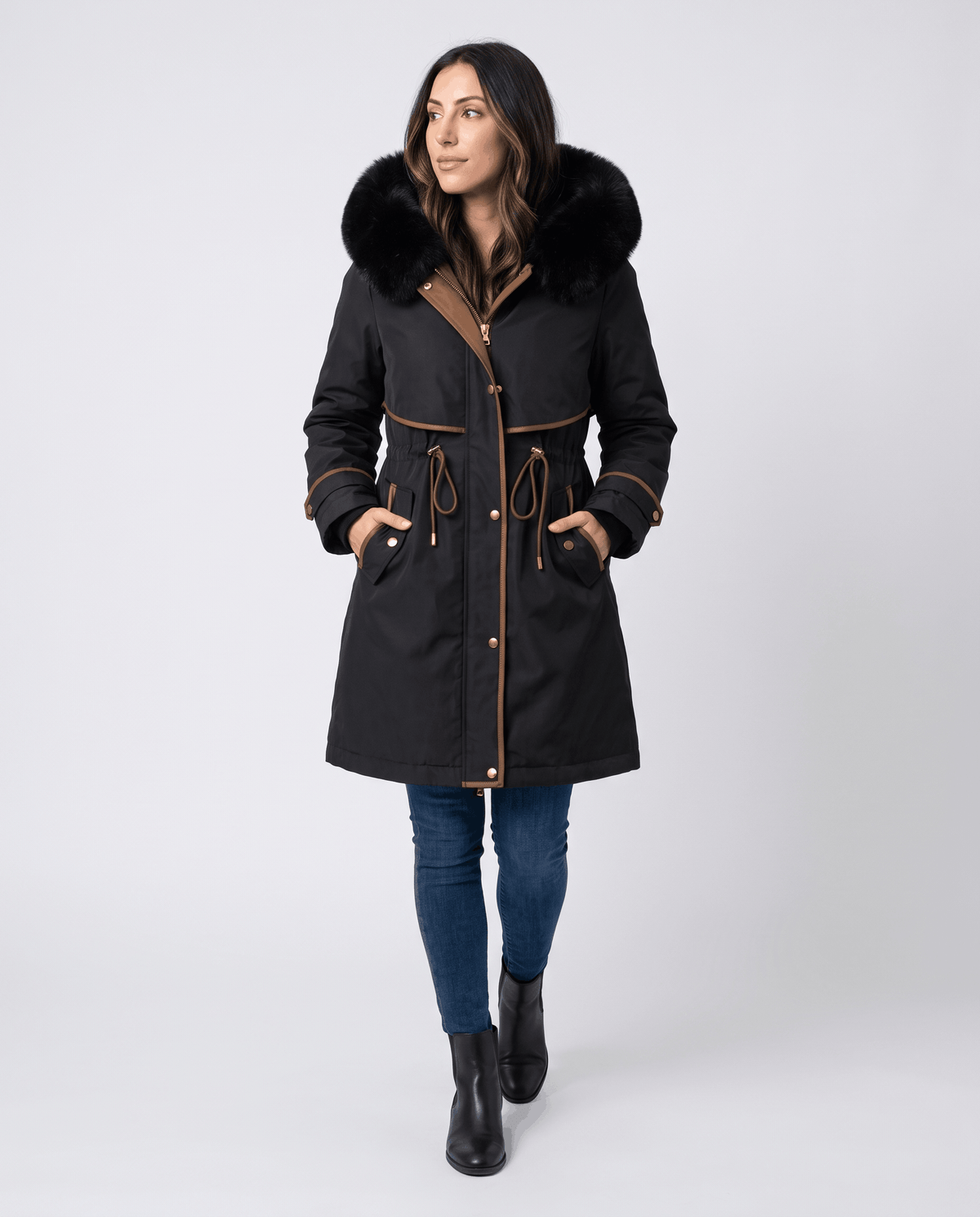 A woman wearing a black winter parka with a plush fur-trimmed hood and adjustable waist, front view