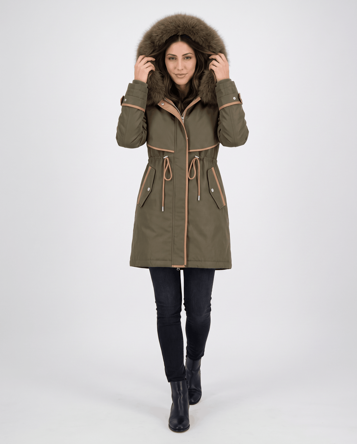 A woman wearing an olive green winter parka with a plush fur-trimmed hood, cozy lining, and adjustable drawstring waist