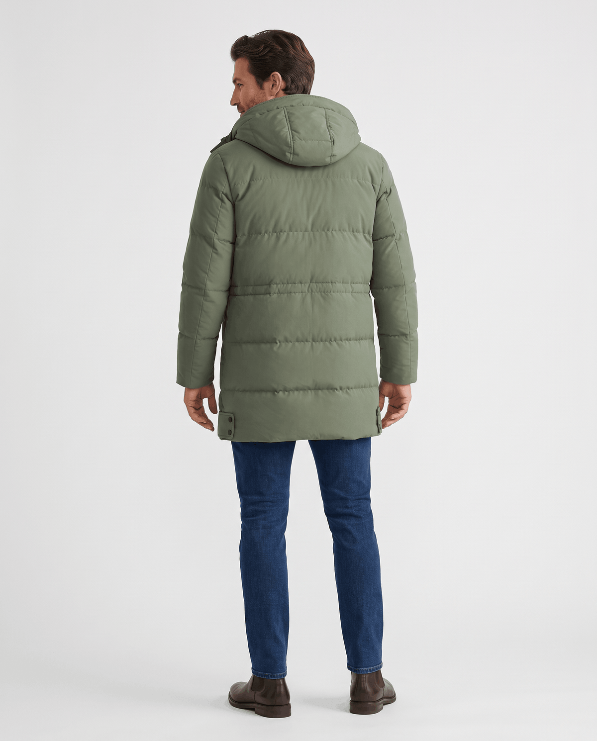 A man wearing an olive green longline puffer parka jacket with a hood, shown from the back
