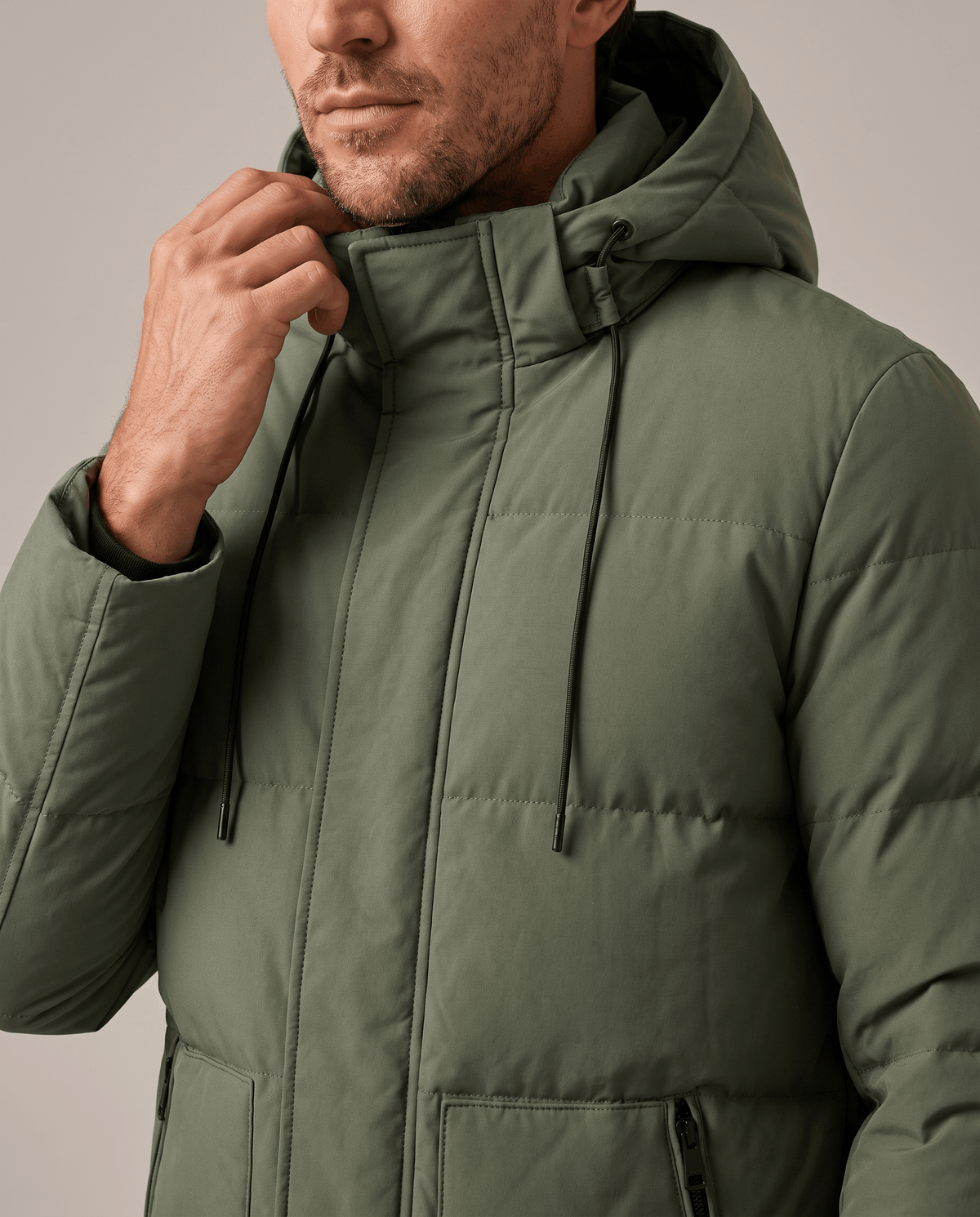 Close-up of a man wearing an olive green hooded puffer parka jacket, showing the insulated quilting and hood detail