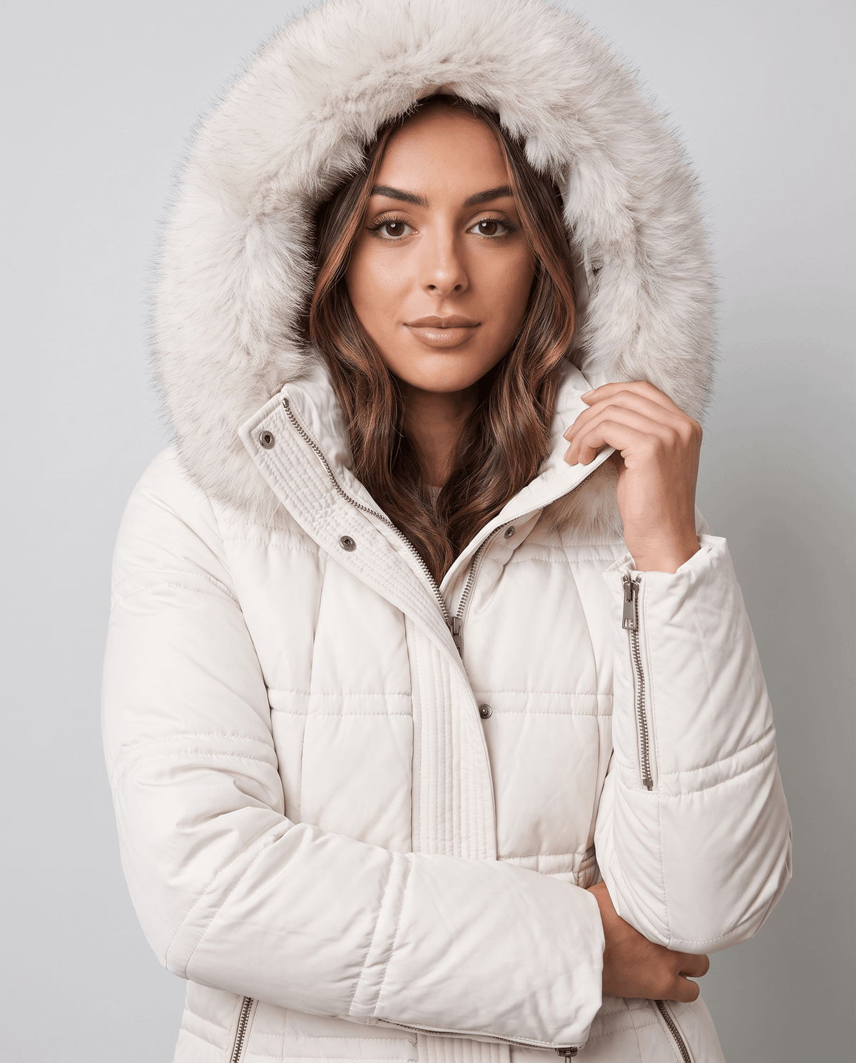 Close-up of a woman wearing a white quilted winter parka, showing the plush fur-trimmed hood and padded design